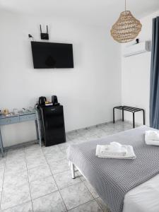 Cette chambre blanche dispose d'une table et d'une télévision. dans l'établissement Eleios Hotel Serifos, à Livadiá