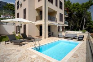 a villa with a swimming pool in front of a building at Seafront Apartment Totally Beachin with Private Pool in Ivan Dolac