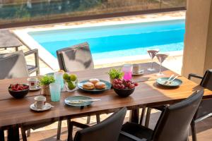 einen Holztisch mit Obstschalen neben einem Pool in der Unterkunft Seafront Apartment Totally Beachin with Private Pool in Ivan Dolac