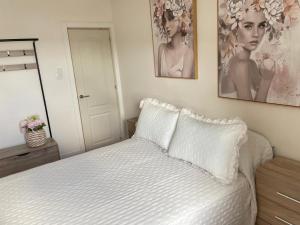 a bedroom with a white bed with two pictures on the wall at Apartamento en Covas in Ferrol