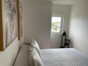 a bedroom with a bed with white sheets and a window at Apartamento en Covas in Ferrol