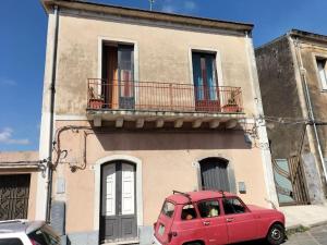 een rode auto geparkeerd voor een gebouw bij Casa Vacanze Relax Etna in San Giovanni la Punta