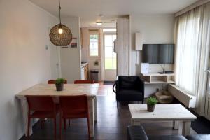 a living room with a table and chairs and a kitchen at 2-person bungalow Heuveltjes in Voorthuizen