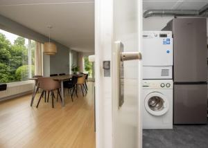 uma cozinha e sala de jantar com uma mesa e uma máquina de lavar roupa em Holidayhouse Bongel 1 Ter Herne em Terherne