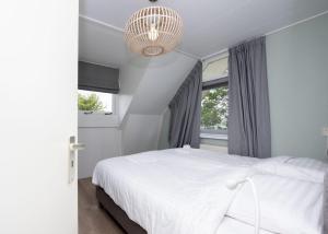 um quarto com uma cama branca e um lustre em Holidayhouse Bongel 1 Ter Herne em Terherne