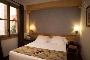 - une chambre avec un lit, deux lampes et une fenêtre dans l'établissement Hotel Pintor El Greco, à Tolède