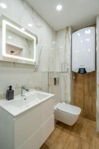 a white bathroom with a sink and a toilet at Zenith Apartment in Sofia