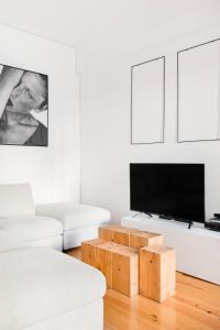 sala de estar con TV y sofá blanco en MY LX FLAT City Center Saldanha, en Lisboa