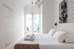 una camera da letto bianca con un letto e asciugamani di MY LX FLAT City Center El Corte Inglês a Lisbona
