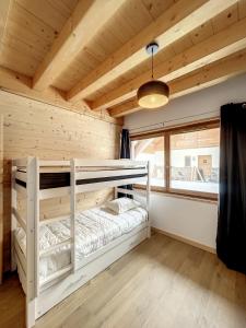 sypialnia z łóżkiem piętrowym w drewnianym domku w obiekcie Chalet Le Charbonnel w mieście La Toussuire