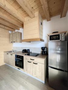 eine Küche mit einem Kühlschrank aus Edelstahl und Holzschränken in der Unterkunft Chalet L'Argentière in La Toussuire
