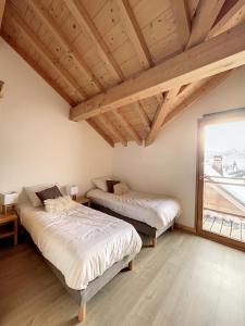 two beds in a room with wooden ceilings at Chalet L'Argentière in La Toussuire