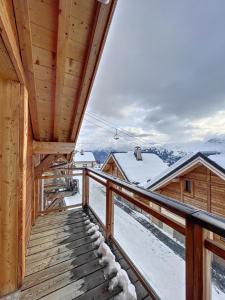 einen Holzbalkon mit Blick auf eine Ski-Lodge in der Unterkunft Chalet L'Argentière in La Toussuire