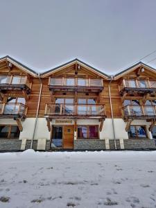 un edificio de madera con nieve delante en Chalet Le Gebroulaz en La Toussuire