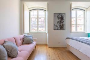 a living room with a pink couch and two windows at MY LX FLAT Luxury Chiado Design Apartment in Lisbon