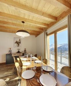 uma sala de jantar com mesa e cadeiras e uma grande janela em Chalet Le Mauntenrojji - skis aux pieds em La Toussuire