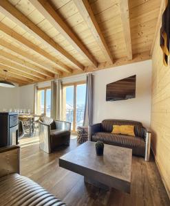 uma sala de estar com um sofá e uma mesa em Chalet Le Mauntenrojji - skis aux pieds em La Toussuire