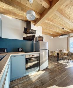 uma cozinha com um frigorífico e uma mesa com cadeiras em Chalet Le Mauntenrojji - skis aux pieds em La Toussuire