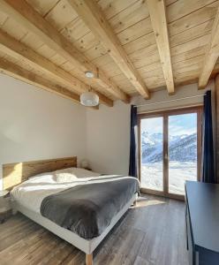 um quarto com uma cama e uma grande janela em Chalet Le Mauntenrojji - skis aux pieds em La Toussuire