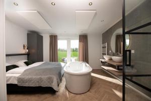 een slaapkamer met een groot bed en een bad bij Panorama lodge with wellness and hottub 2 p. in Rijssen
