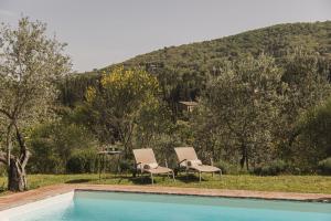 two chairs and a swimming pool with a mountain in the background at La Veronica Exclusive Chianti Resort in Greve in Chianti