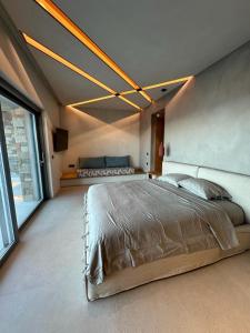 1 dormitorio con cama grande y ventana grande en Syros Soul Private Pool Suites, en Ermoupoli