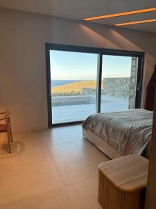 Syros Soul Private Pool Suites في إرموبولّي: غرفة نوم مع باب زجاجي كبير مع اطلالة