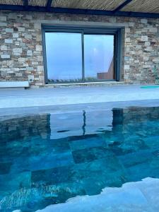 una piscina frente a un edificio con ventana en Syros Soul Private Pool Suites en Ermoupoli