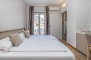 sypialnia z 2 łóżkami i balkonem w obiekcie Garden House - Hotel Sport w mieście Levico Terme