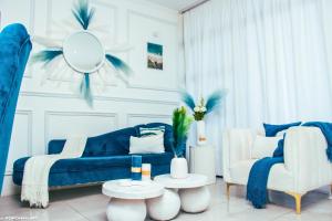 sala de estar con sofá azul y 2 sillas en Blue Waves Luxury Apartment- Power Backup, en Johannesburgo
