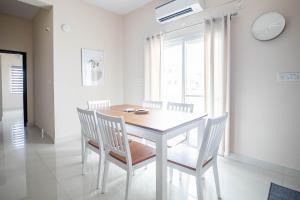 a white dining room with a table and chairs at MyHaus Apartments in Hyderabad