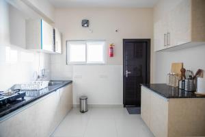 a white kitchen with a black door and a counter at MyHaus Apartments in Hyderabad +35 photos