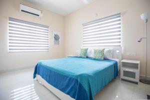 a bedroom with a bed with blue sheets and windows at MyHaus Apartments in Hyderabad
