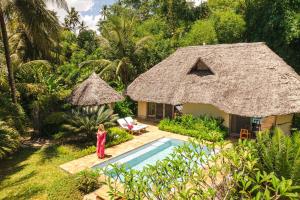 une femme debout devant une maison avec piscine dans l'établissement Zanzi Resort, à Zanzibar City