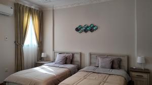 a bedroom with two beds and a clock on the wall at Sada Compound (Women Only) سيدات فقط in Riyadh