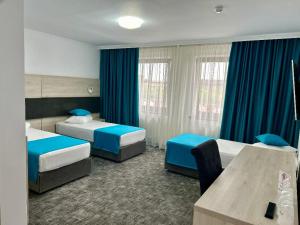 Habitación de hotel con 2 camas y cortinas azules en Hotel Bliss, en Roman