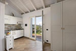 a kitchen with white cabinets and a sliding glass door at Studio Nido in Pompeiana