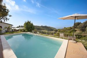 a swimming pool with an umbrella and chairs at Studio Nido in Pompeiana