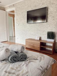 een slaapkamer met handdoeken op een bed en een tv aan de muur bij Cozy House in Lazarevac