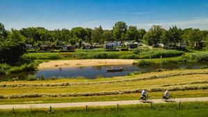 two people riding bikes in a river with a boat at Mobile home by the Regge I 4 people in Zuna