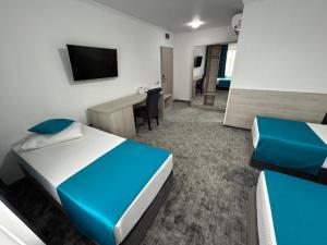 Pokój z 2 łóżkami, biurkiem i telewizorem w obiekcie Hotel Bliss w mieście Roman