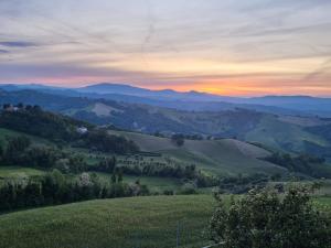 a sunset over a green field with mountains in the background at Country House Ca' Brunello in Urbino
