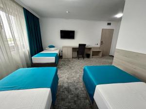 Habitación de hotel con 2 camas y escritorio en Hotel Bliss, en Roman