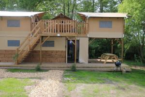 a large house with a deck and a porch at Treehouse tent at the Regge with private sanitary facilities 6 people in Zuna