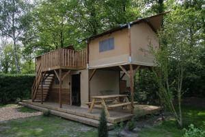 a tree house with a porch and a deck at Treehouse tent at the Regge with private sanitary facilities 6 people in Zuna