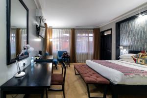 a hotel room with a bed and a desk with a desk at A'lure Hotel & Residences in Kampala