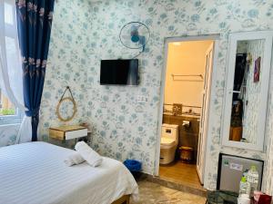Villa - Hotel Nam Khang 2 Dalat في دالات: غرفة نوم مع سرير وتلفزيون على الحائط