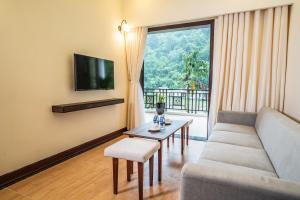 een woonkamer met een bank, een tafel en een tv bij Saigon-Ba Be Resort in Ba Be18