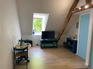 ein Wohnzimmer mit einem TV und Holzböden in der Unterkunft Chambre double avec salle de bains privée in Quintin