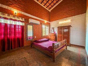Royal Experiences Chettinad Sea Side Villa, Kanathur ECR Chennai في تشيناي: غرفة نوم بسرير في جدار من الطوب
